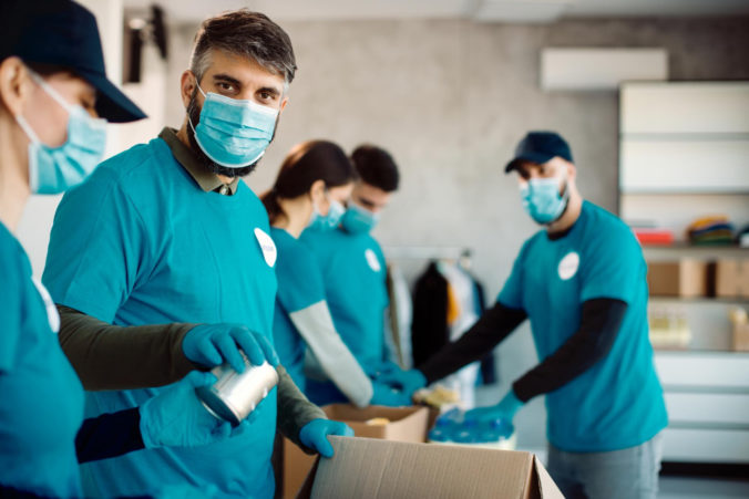 group people with protective face masks packing donation boxes food charity 676x451